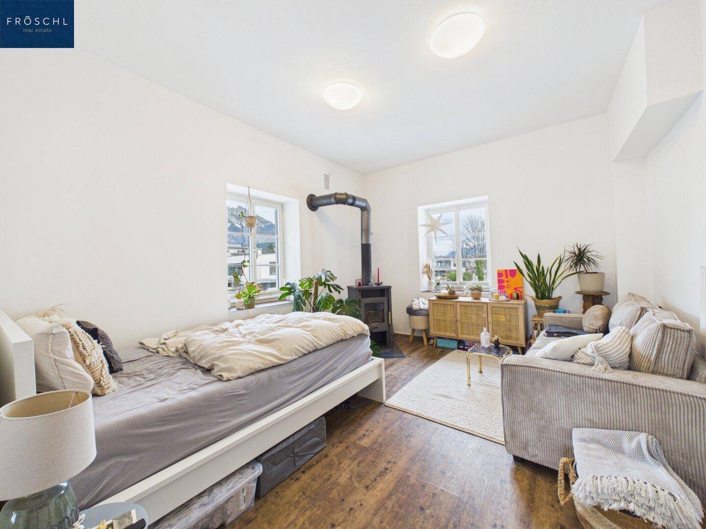 Helles Schlafzimmer mit Holzboden, Kaminofen und Blick ins Grüne.