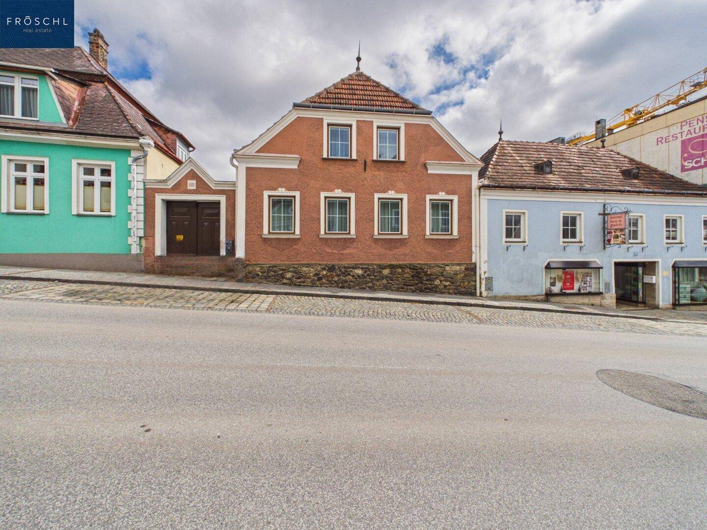 Historisches Gebäude mit orangeroter Fassade und traditioneller Architektur an einer Straße.