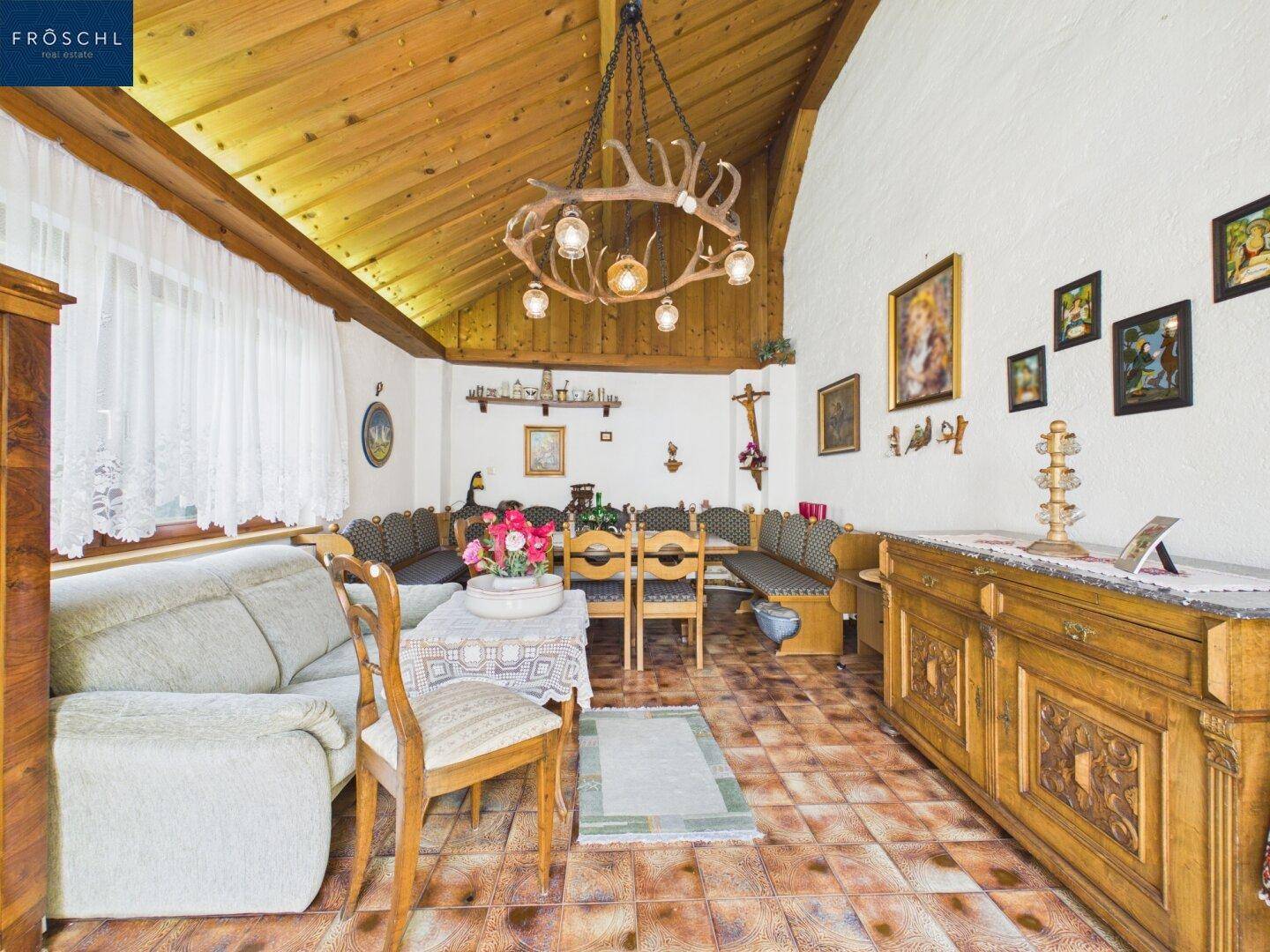 Rustikales Wohnzimmer mit Holzbalkendecke, Kachelboden und traditioneller Einrichtung.