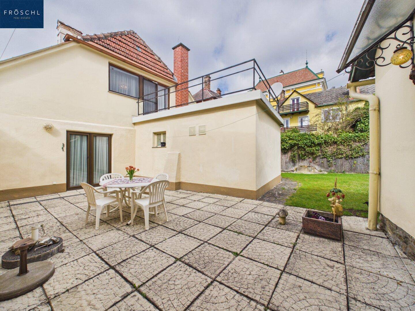 Geräumige gepflasterte Terrasse mit Gartenmöbeln und Blick auf den Gartenbereich.