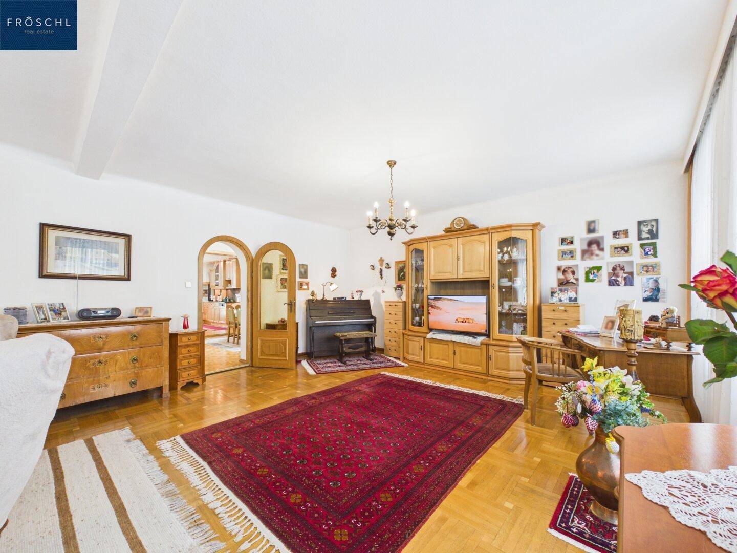 Geräumiges Wohnzimmer mit Parkettboden, traditionellen Möbeln und großem Teppich.