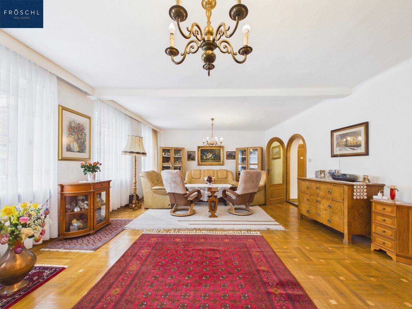 Großes Wohnzimmer mit Parkettboden, Kronleuchter und traditioneller Einrichtung.