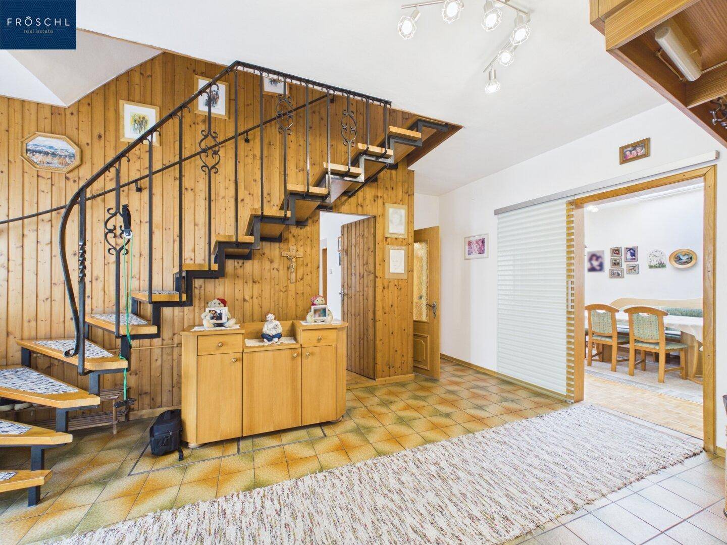Geräumiger Flur mit Holzvertäfelung, gefliestem Boden und geschwungener Treppe.