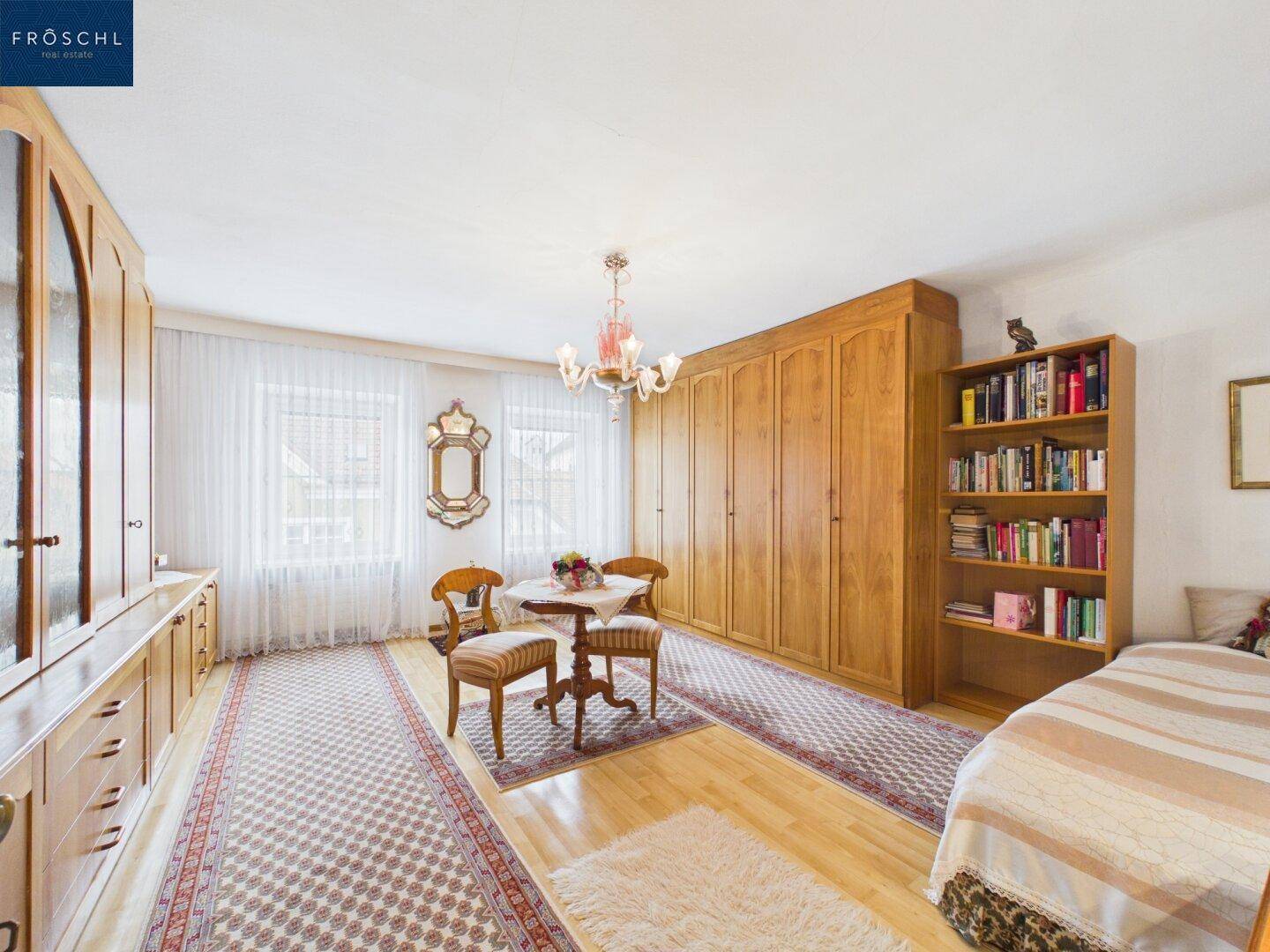Geräumiges Schlafzimmer mit Parkettboden, großen Schränken und Sitzbereich.