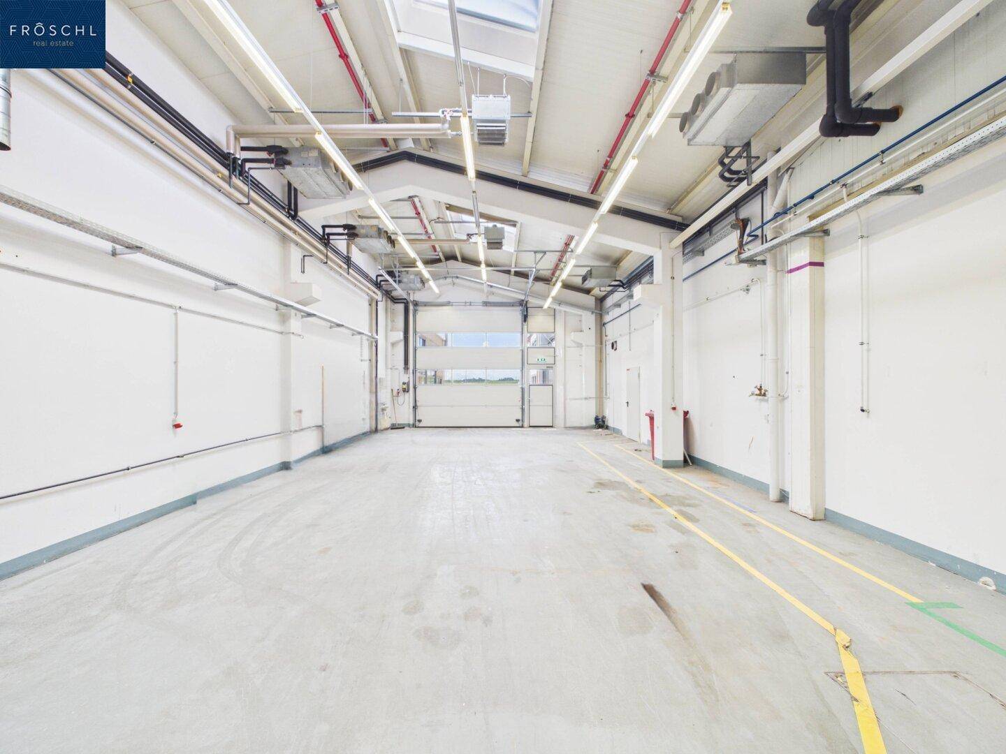 Industriehalle mit großem Rolltor, Betonboden und hohen Decken, ideal für Anlieferung und Lagerung.
