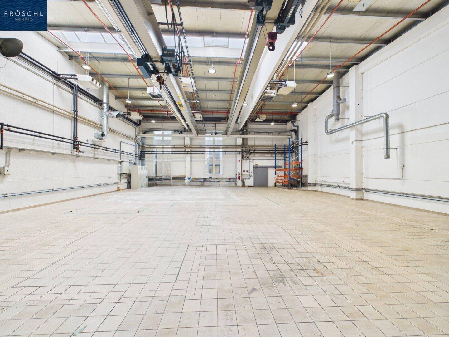 Große Industriehalle mit gefliestem Boden, hohen Decken und einem Blick auf den hinteren Bereich.