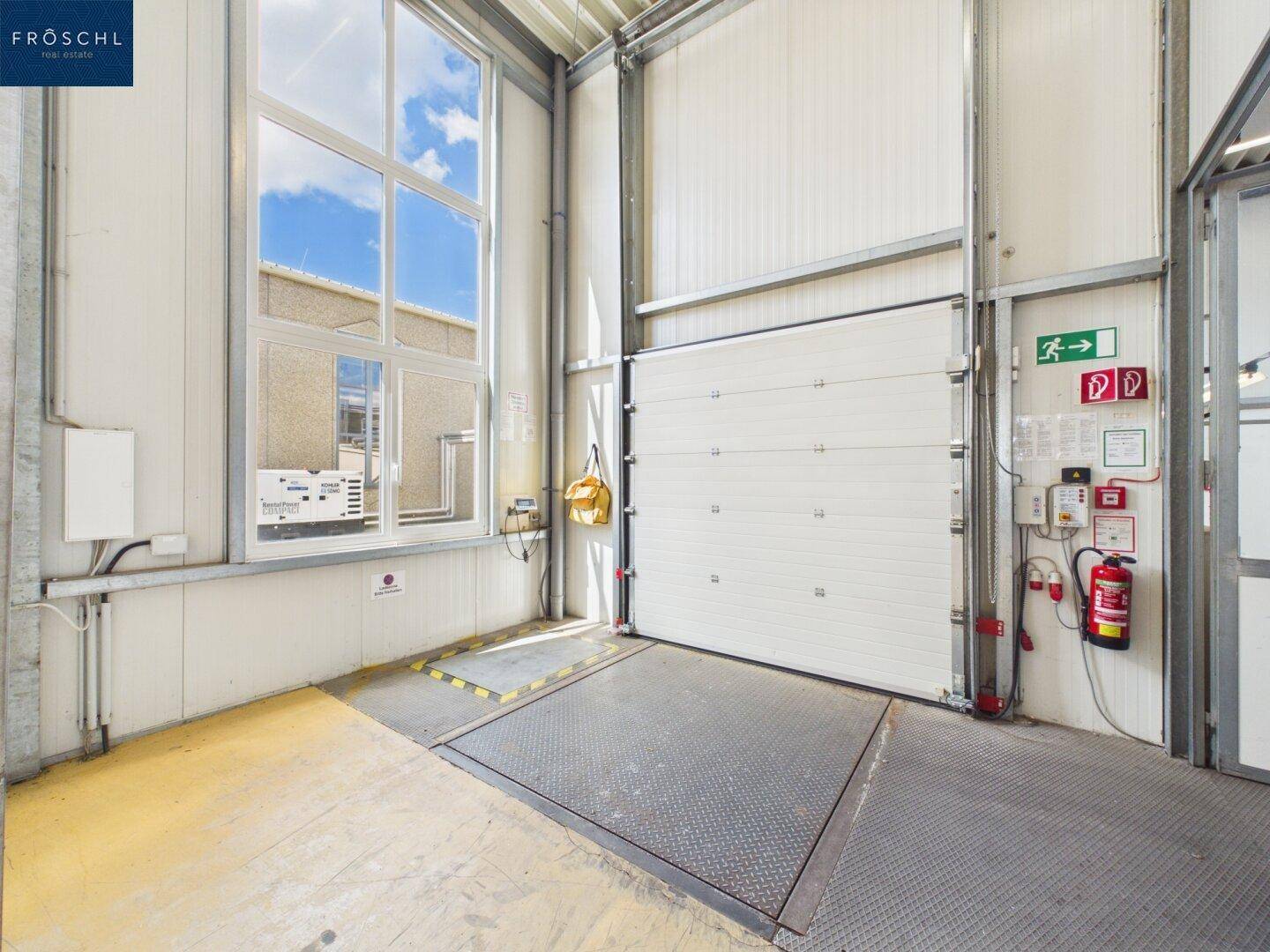 Detailansicht einer Laderampe mit großem Fenster, Rolltor und Sicherheitsausrüstung.