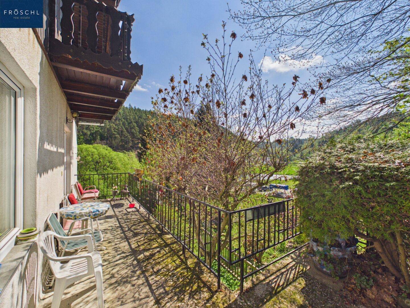 Balkon mit Sitzgelegenheiten und weitem Blick über die grüne Landschaft.