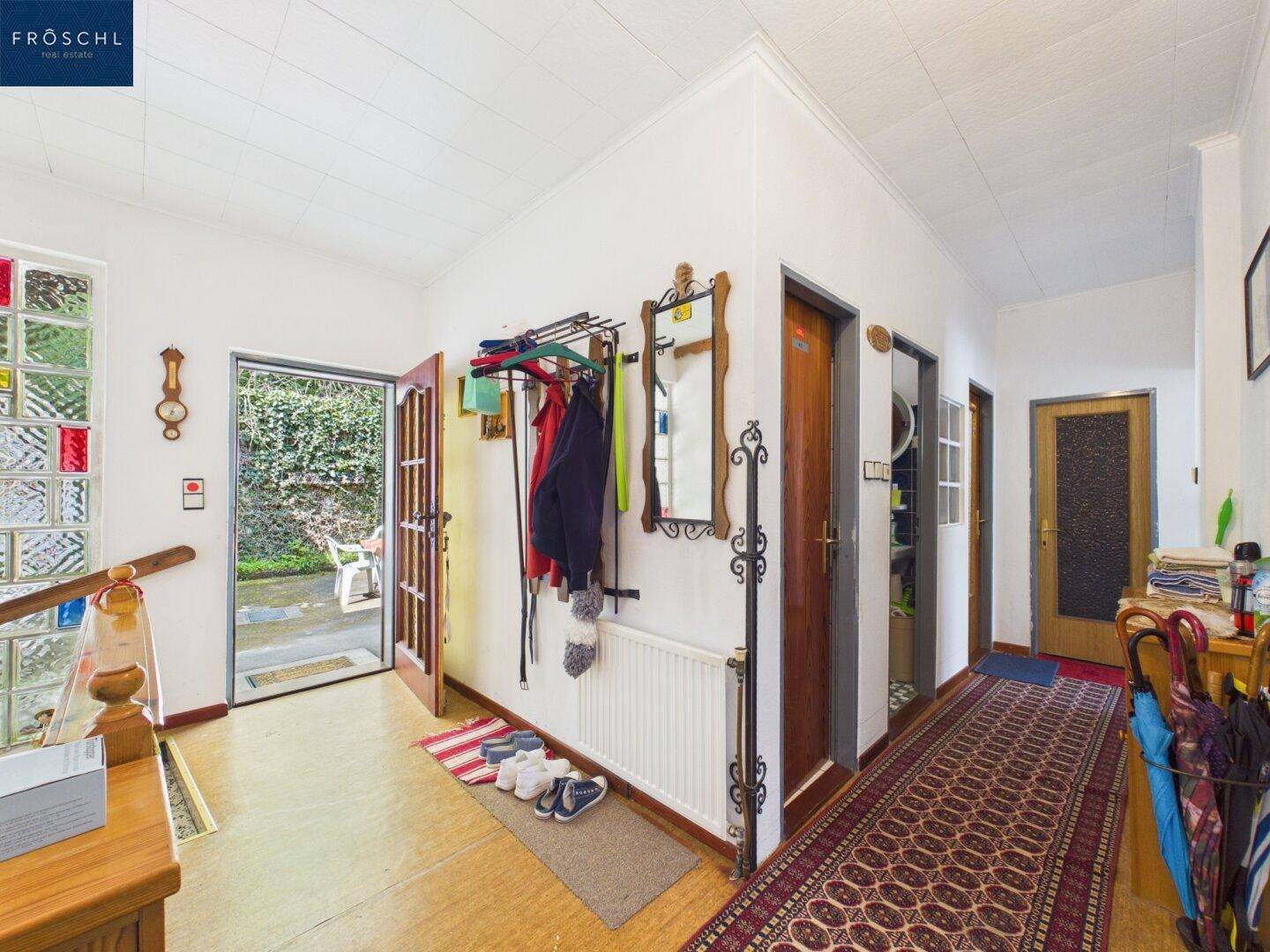 Heller Eingangsbereich mit Garderobe, Spiegel und Zugang zum Garten.