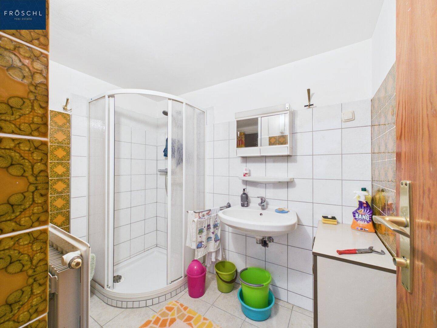 Badezimmer mit Duschkabine, weißen Fliesen und einem Heizkörper.