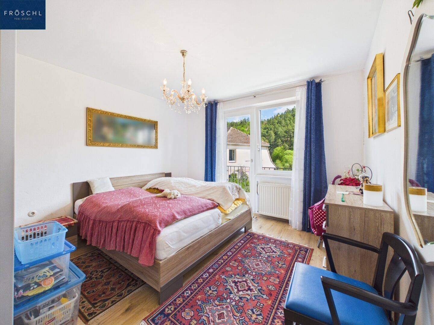 Helles Schlafzimmer mit Doppelbett, Kronleuchter und Zugang zum Balkon.