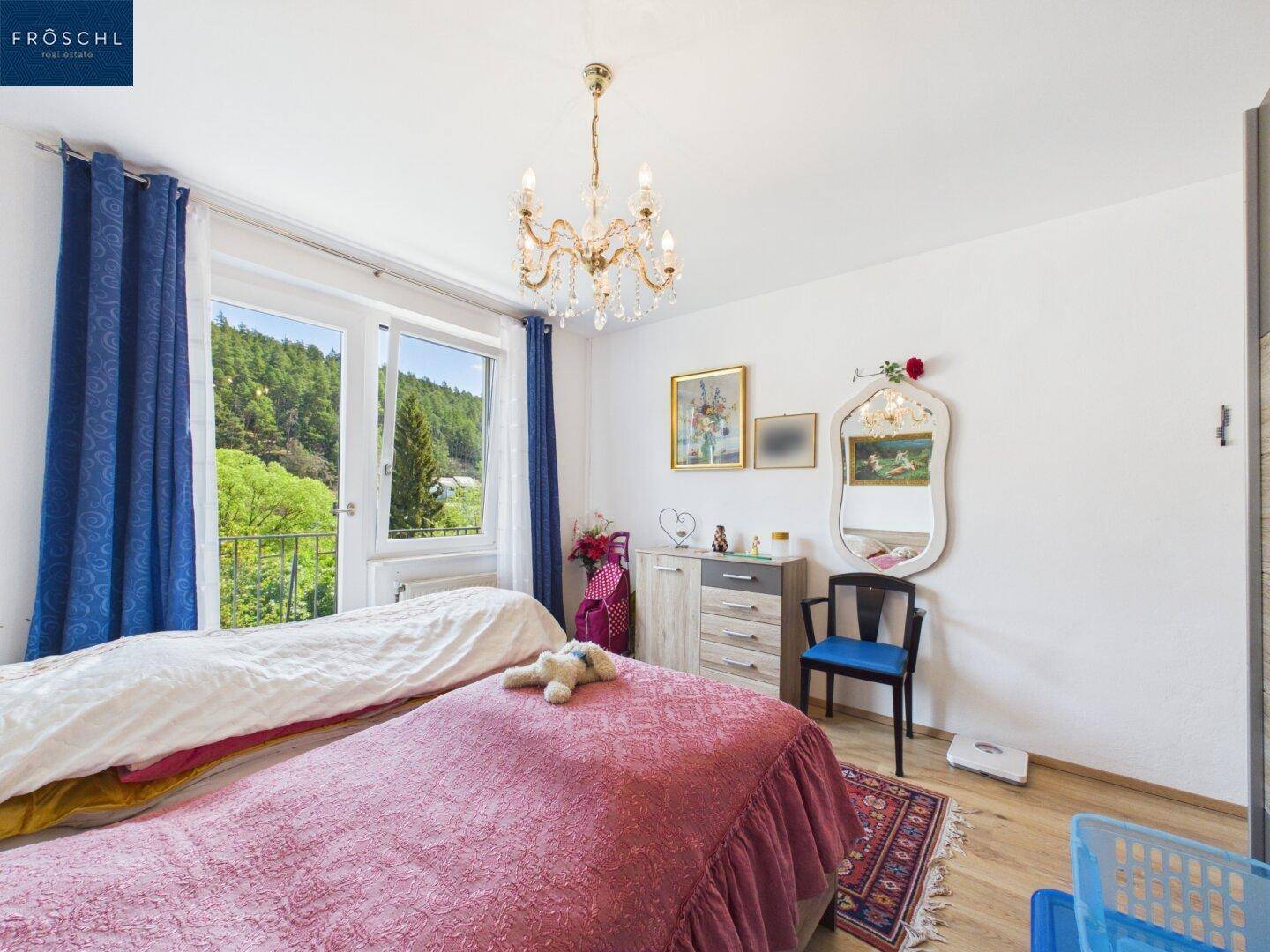 Schlafzimmer mit Doppelbett, Kommode und Blick auf die umliegende Natur.