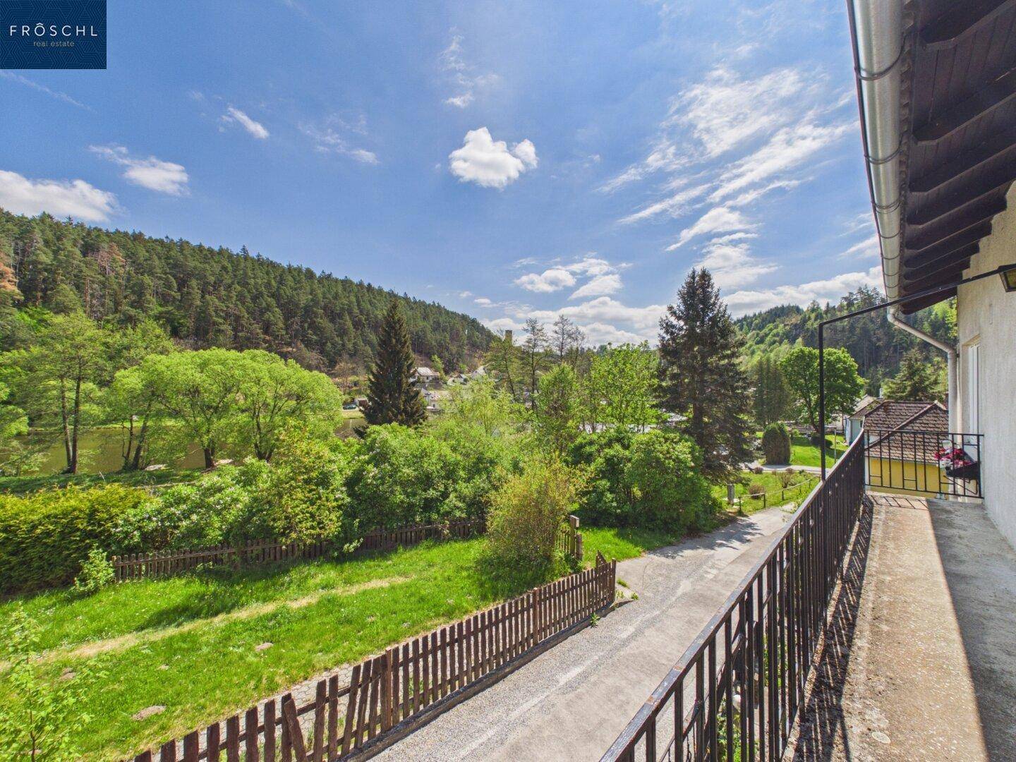 Langer Balkon mit Metallgeländer und weitem Blick über die grüne Landschaft.