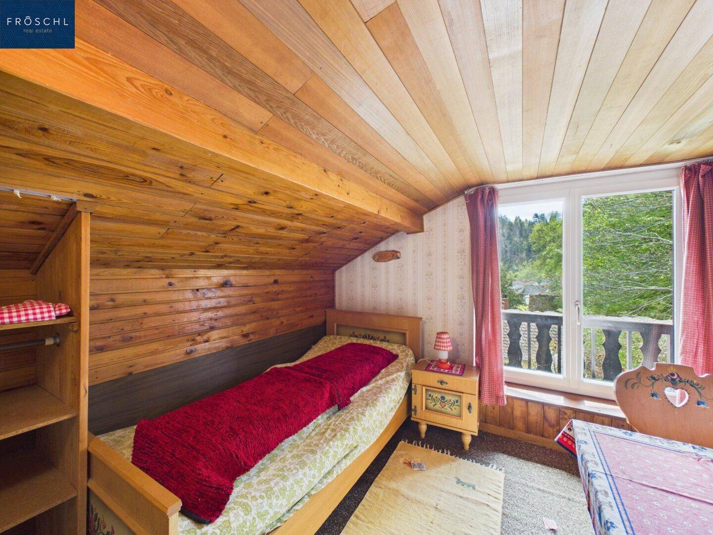Gemütliches Schlafzimmer im Dachgeschoss mit Holzverkleidung und Einzelbett.