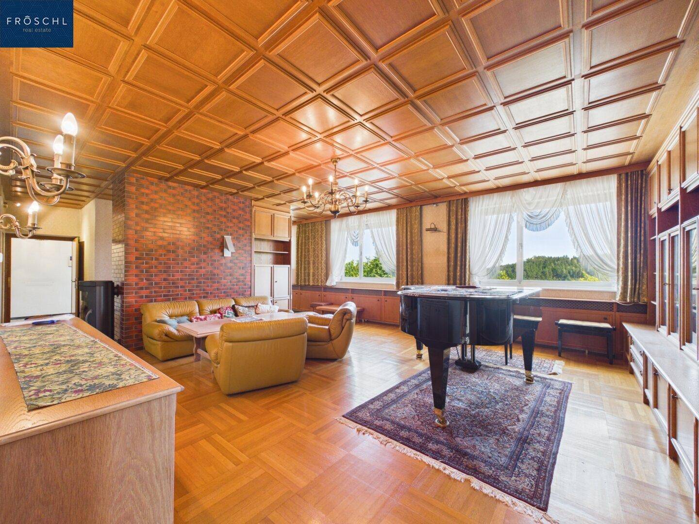 Geräumiges Wohnzimmer mit Holzkassettendecke, Parkettboden und einem Flügel.
