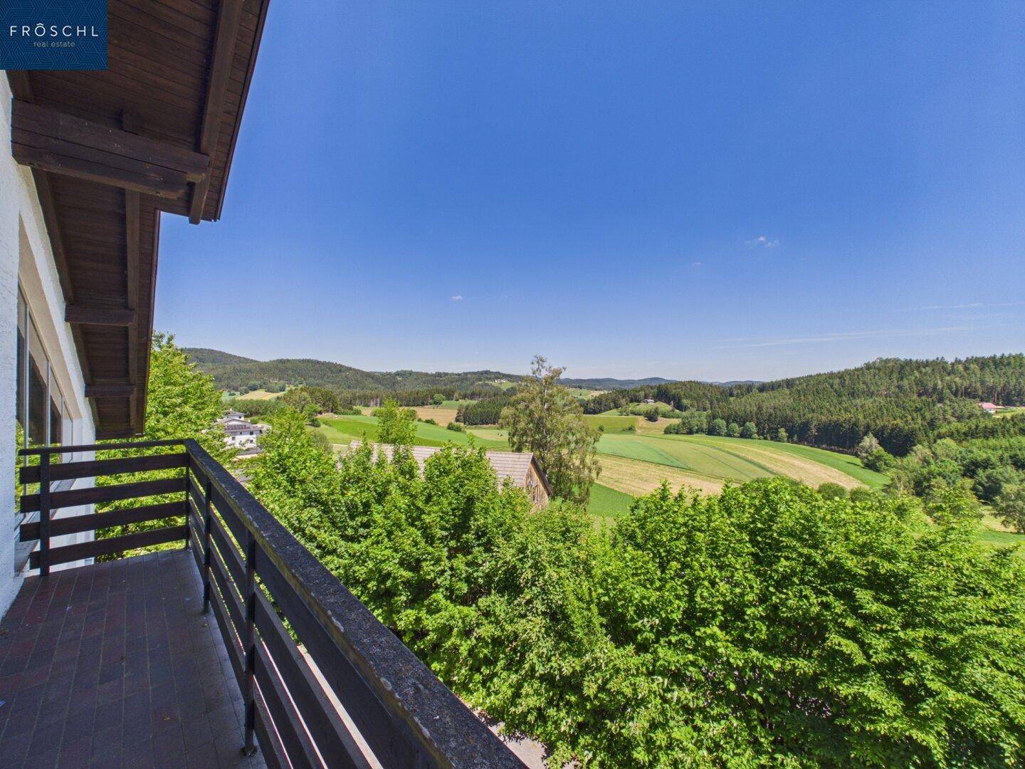 Geräumiger Balkon mit Holzboden und weitem Blick über die Landschaft.