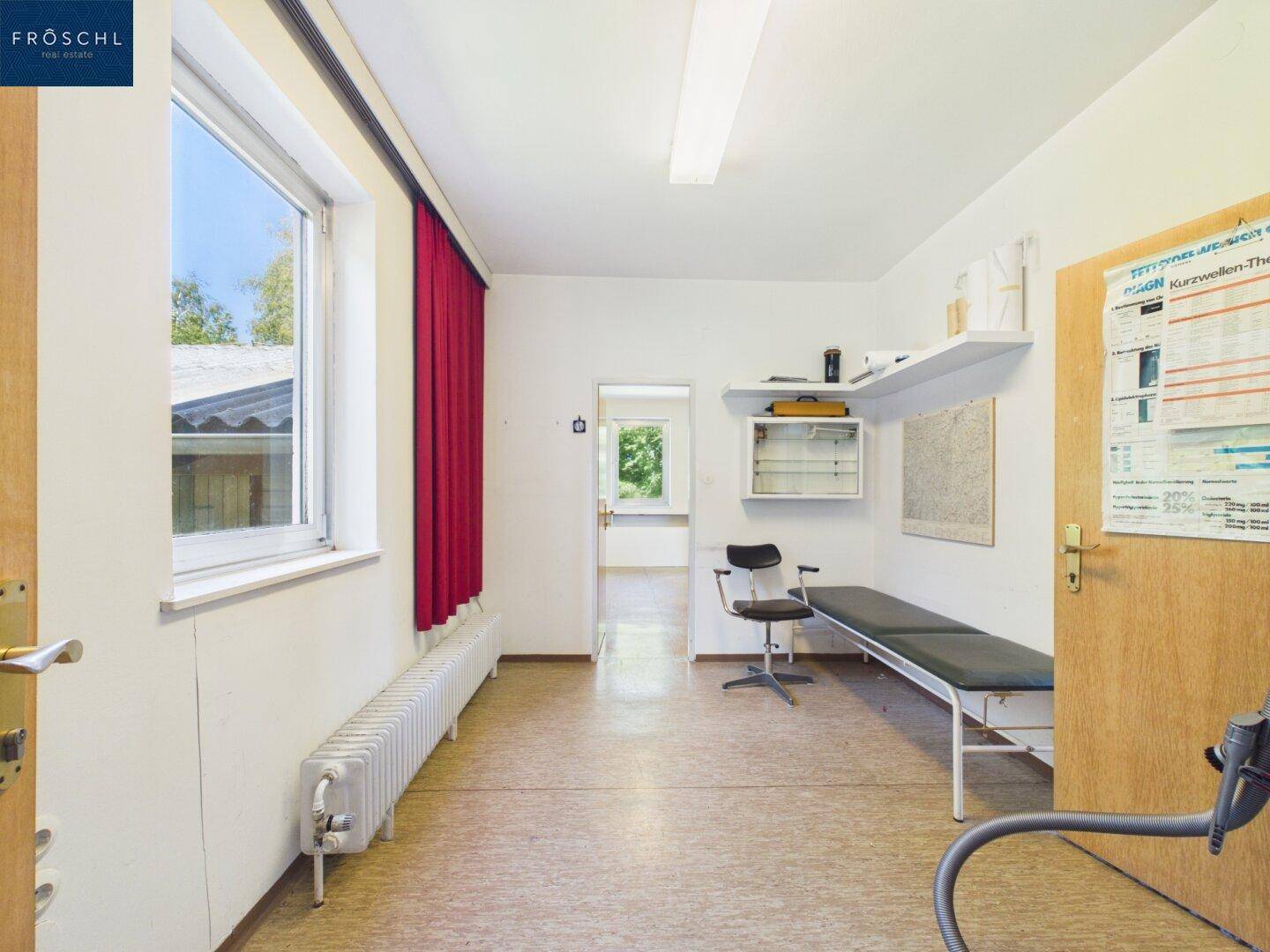 Mehrzweckraum mit Fenster, Liege und Schreibtischbereich, ideal als Büro oder Behandlungsraum.