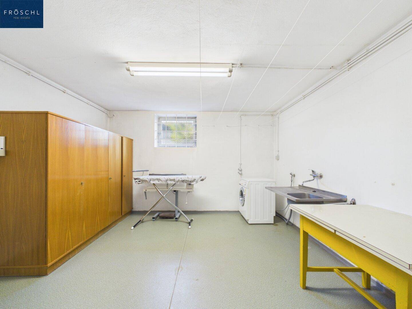 Praktischer Hauswirtschaftsraum im Keller mit Waschmaschine, Spülbecken und Stauraum.