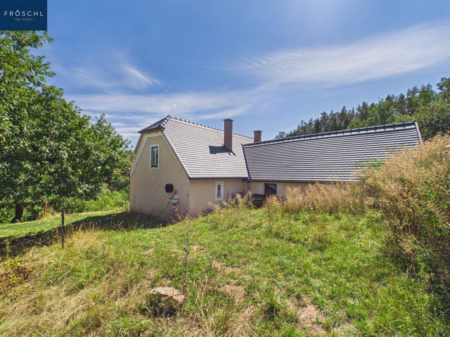 Ländliches Haus mit traditioneller Architektur und umgebender Natur unter einem klaren Himmel.