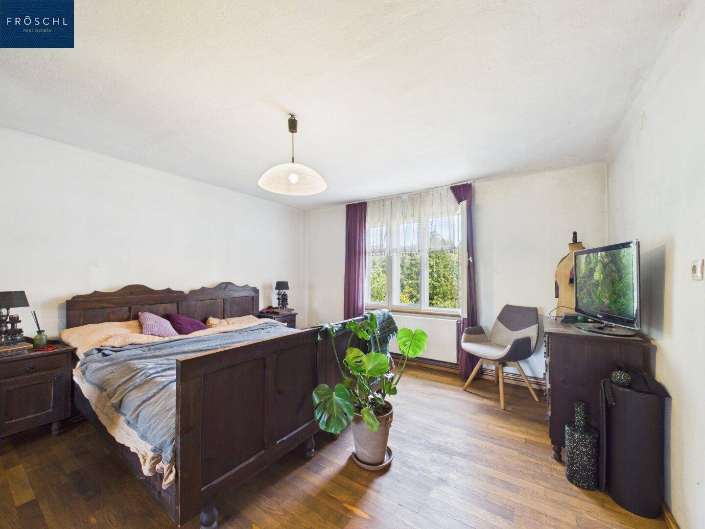 Geräumiges Schlafzimmer mit Holzboden, traditionellem Bett und Blick in den Garten.