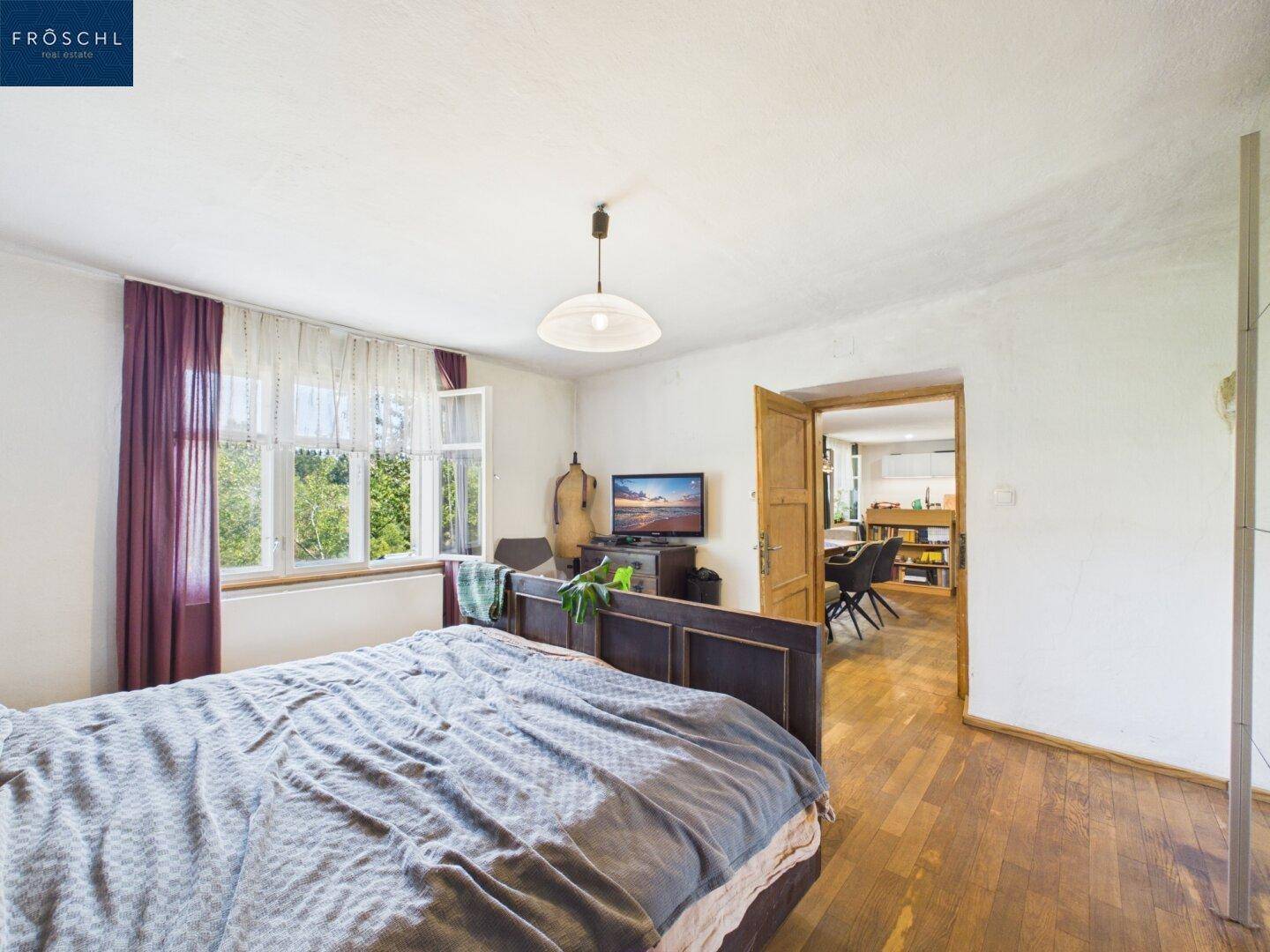 Helles Schlafzimmer mit Holzboden und Zugang zum offenen Wohnbereich.