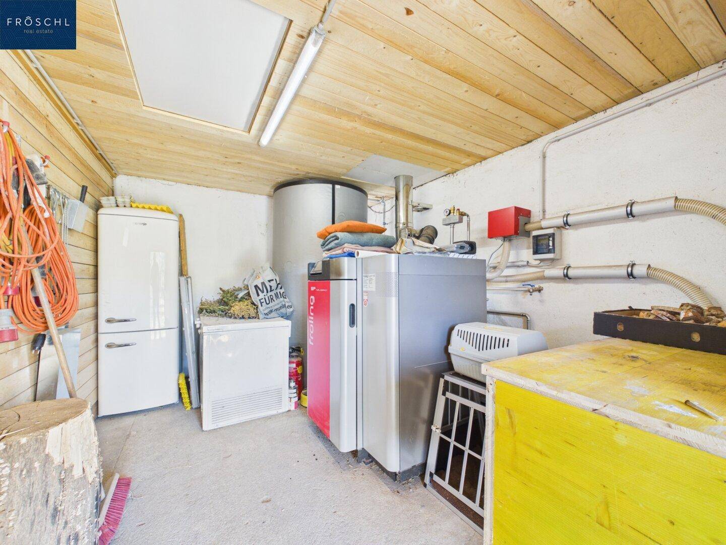 Technikraum mit Heizungsanlage, Warmwasserspeicher und Holzdecke.