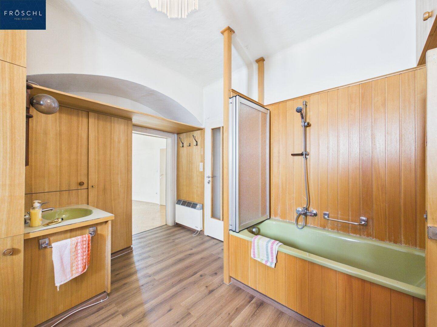 Badezimmer mit Holzverkleidung, einer grünen Badewanne und einem passenden Waschbecken im Vintage-Stil.