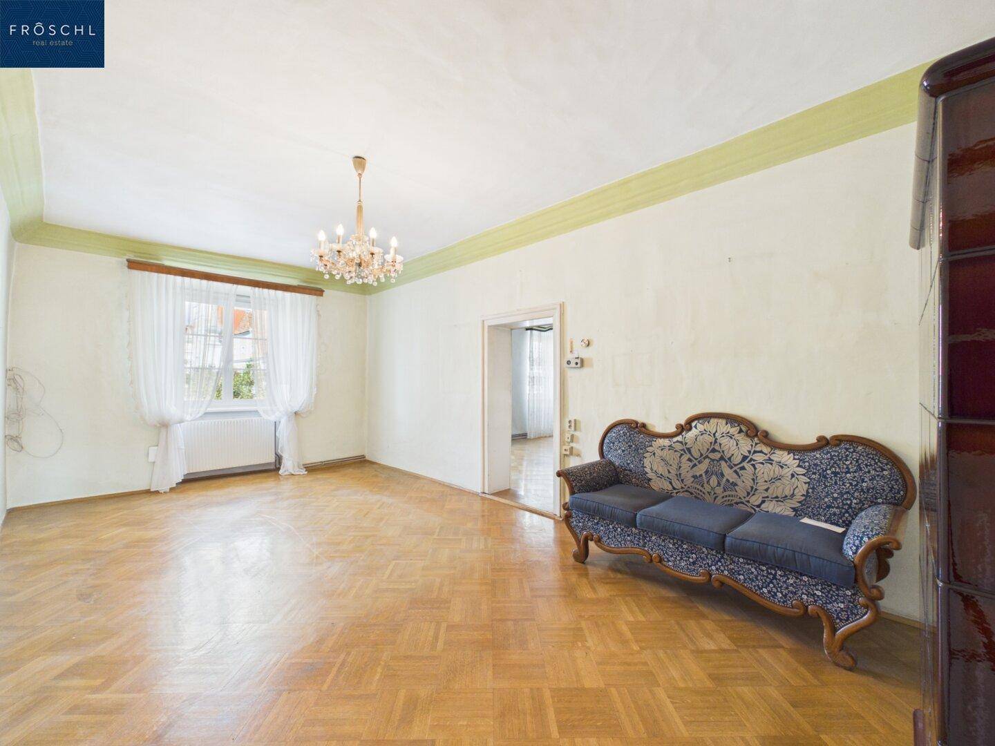 Gemütliches Wohnzimmer mit Parkettboden, einem antiken Sofa und einem traditionellen Kachelofen.