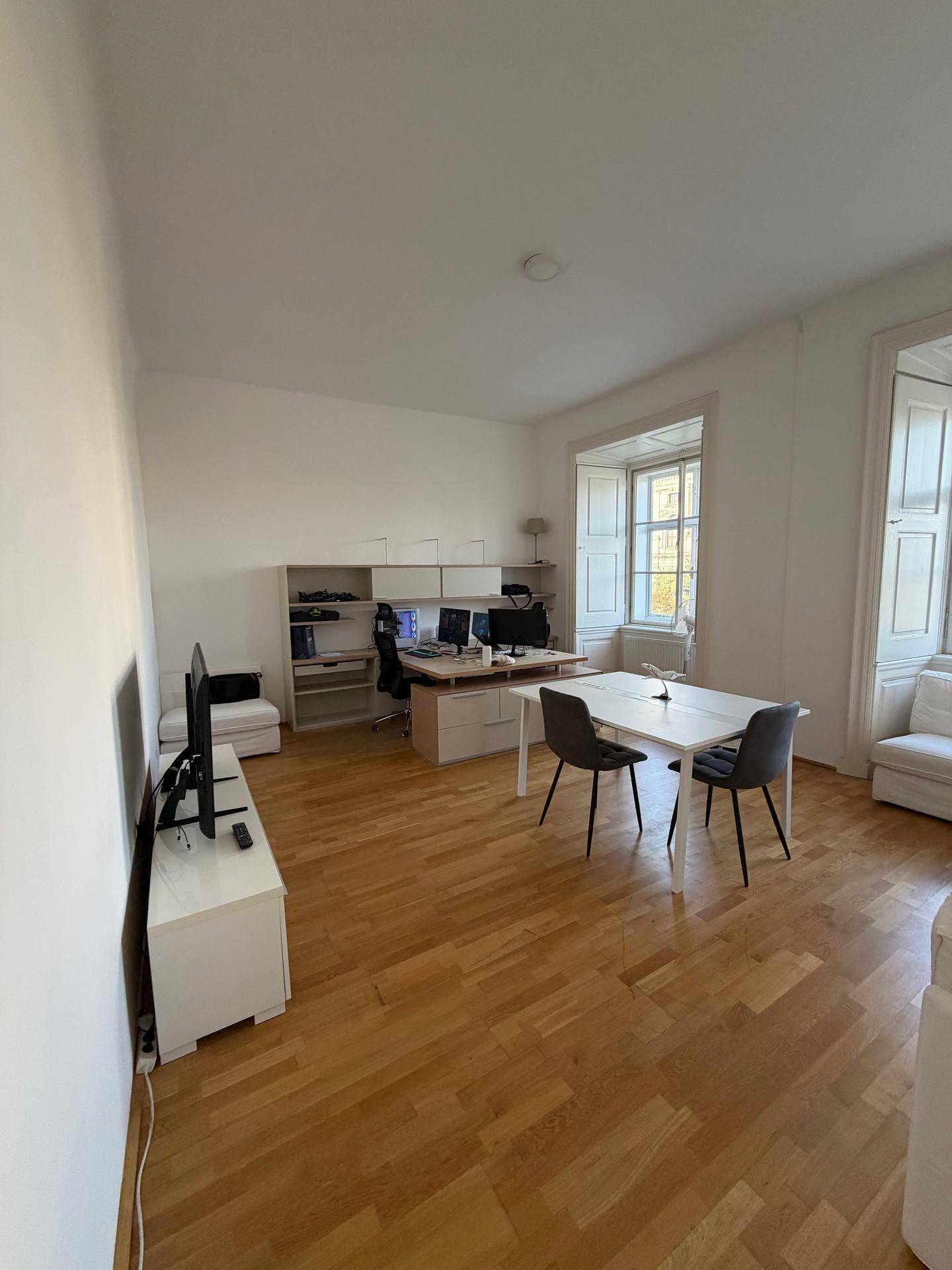 Heller Wohnbereich, der auch als Büro genutzt wird, mit Holzfußboden und großen Fenstern.