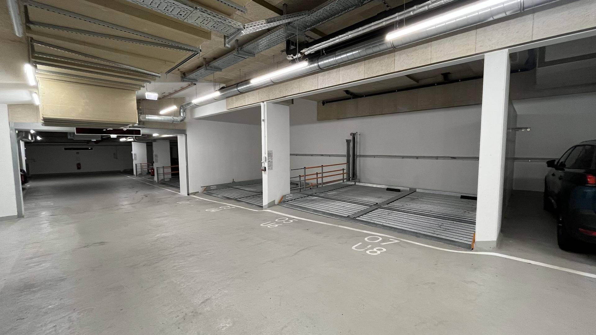 Geräumige Tiefgarage mit modernen Parkliftsystemen und Betonboden.