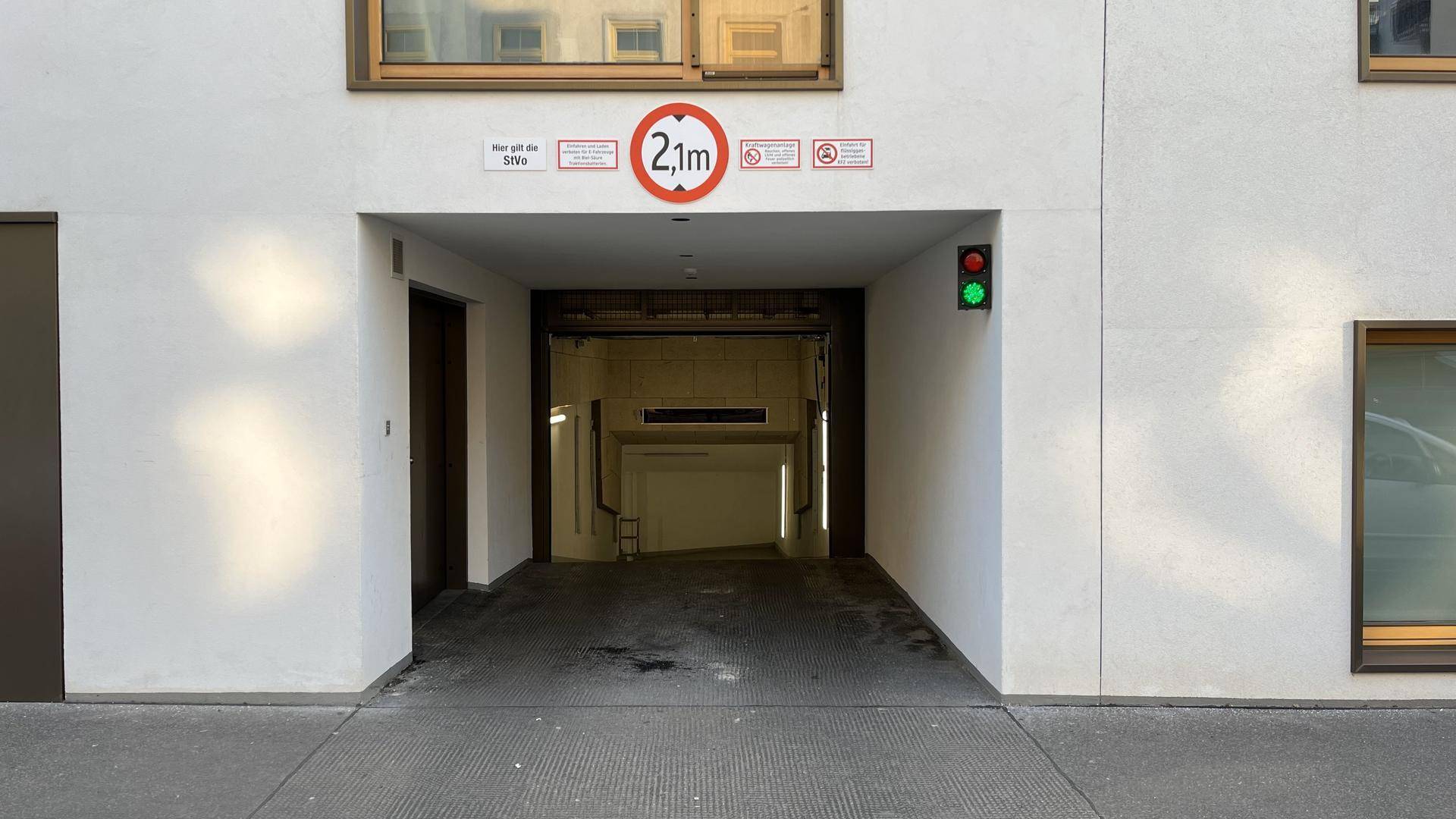 Eingang zur Tiefgarage eines modernen Gebäudes mit Höhenbegrenzung und Ampelsystem.