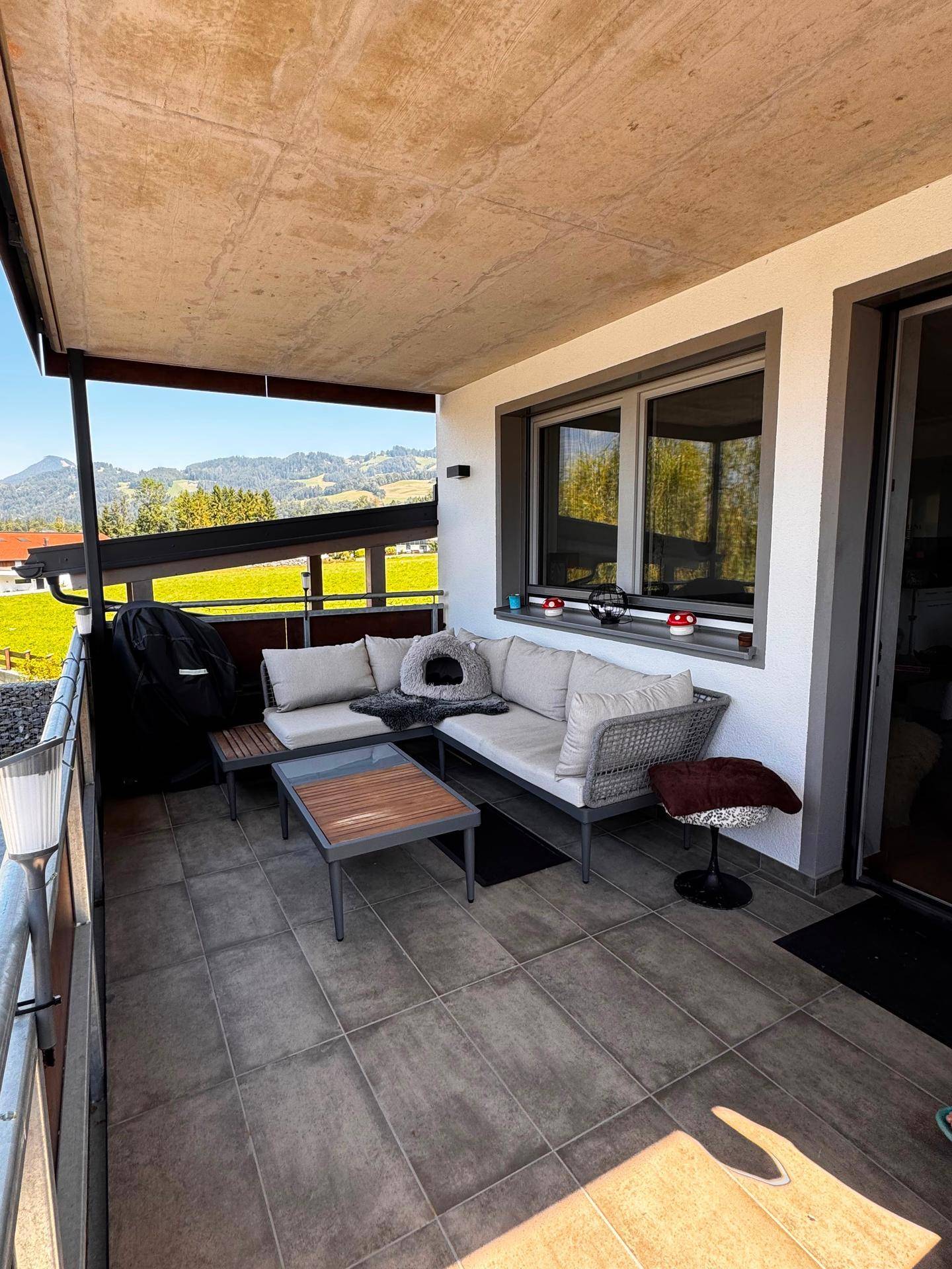 Möblierter Balkon mit Fliesenboden und bequemen Sitzgelegenheiten, ideal zum Entspannen.