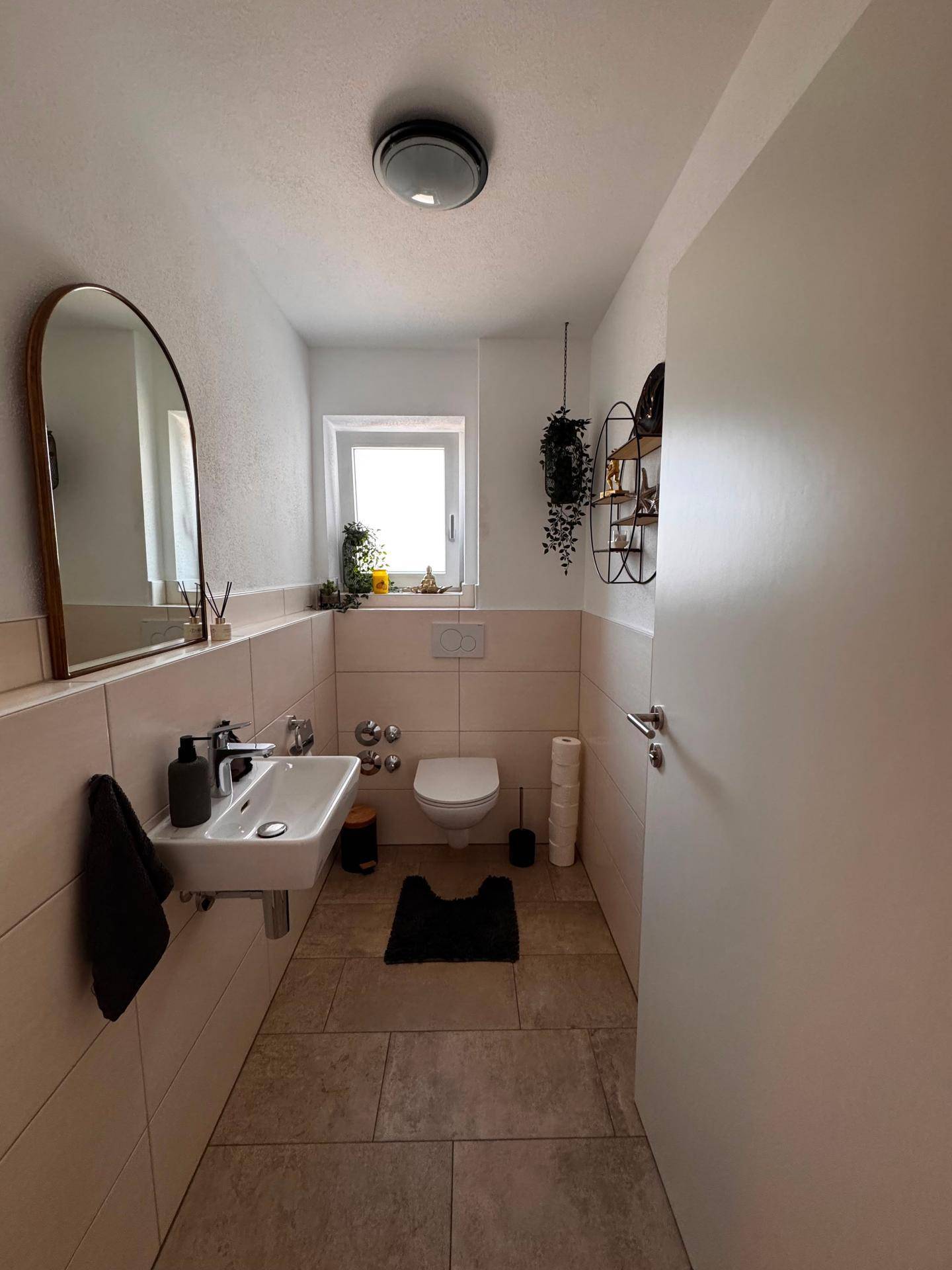 Modernes Gäste-WC mit Wand-WC, Waschbecken und Fenster für natürliches Licht.
