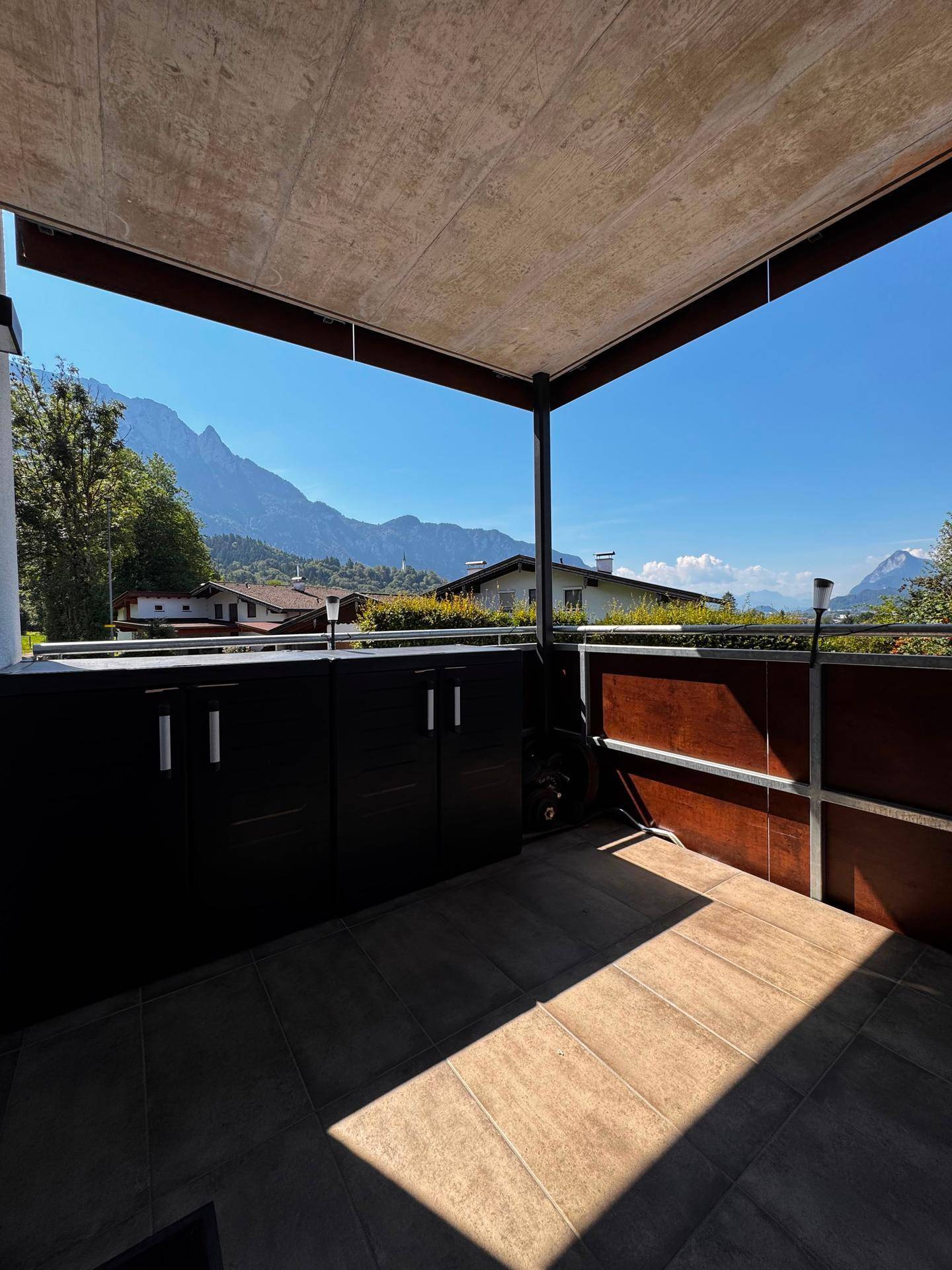 Überdachter Balkon mit Stauraum und weitem Blick auf die umliegende Berglandschaft.