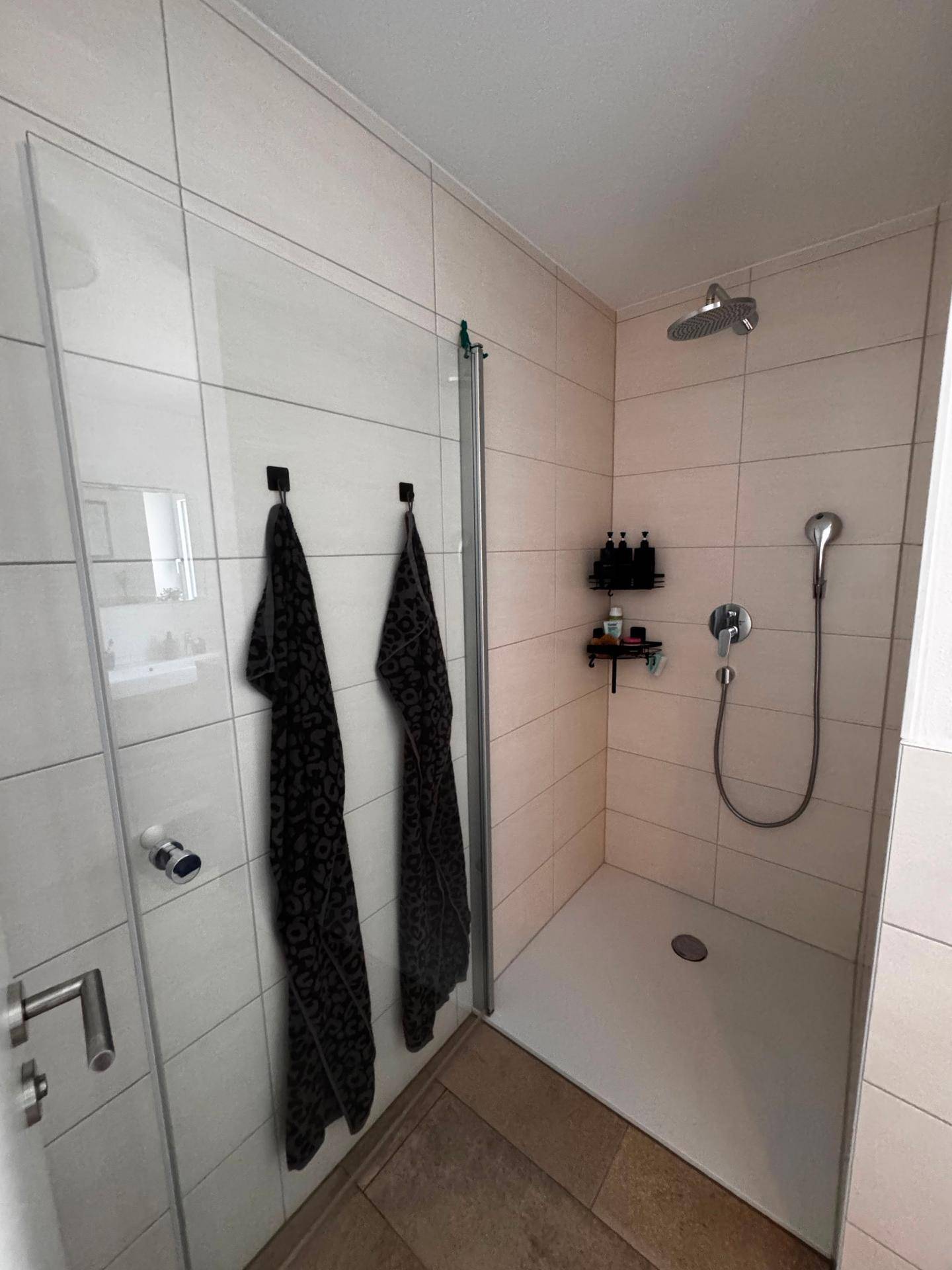 Moderne, begehbare Dusche mit Regenduschkopf und hellen Fliesen im Badezimmer.