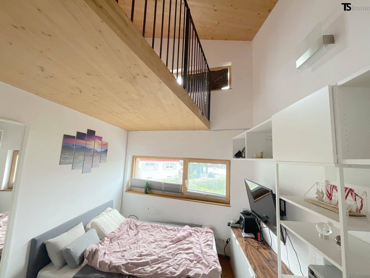 Schlafzimmer mit hoher Decke, Holzdecke und einer offenen Galerie im oberen Bereich.