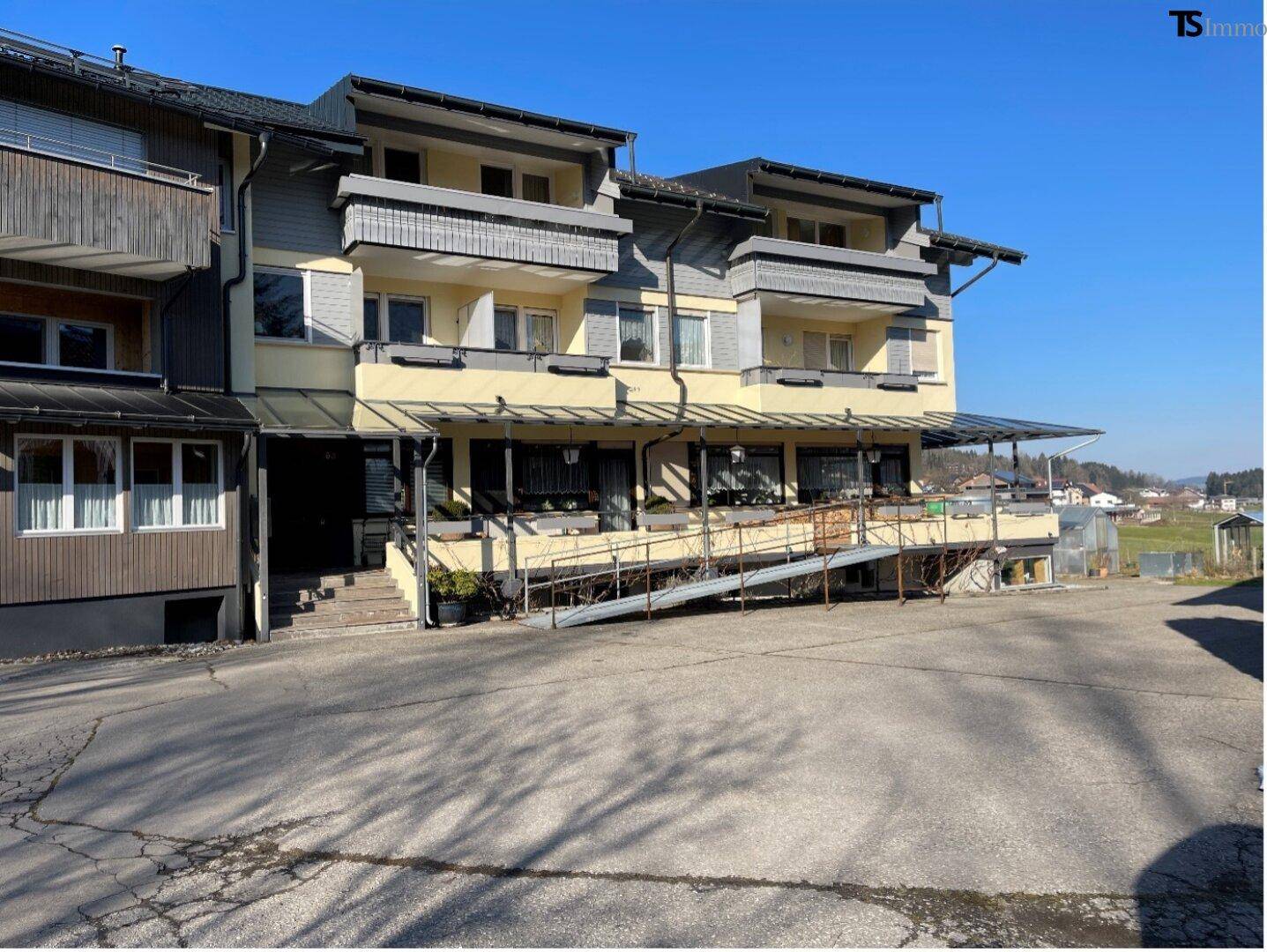 Vorderseite eines mehrstöckigen Gebäudes mit Balkonen und einer Rampe zum Eingangsbereich.