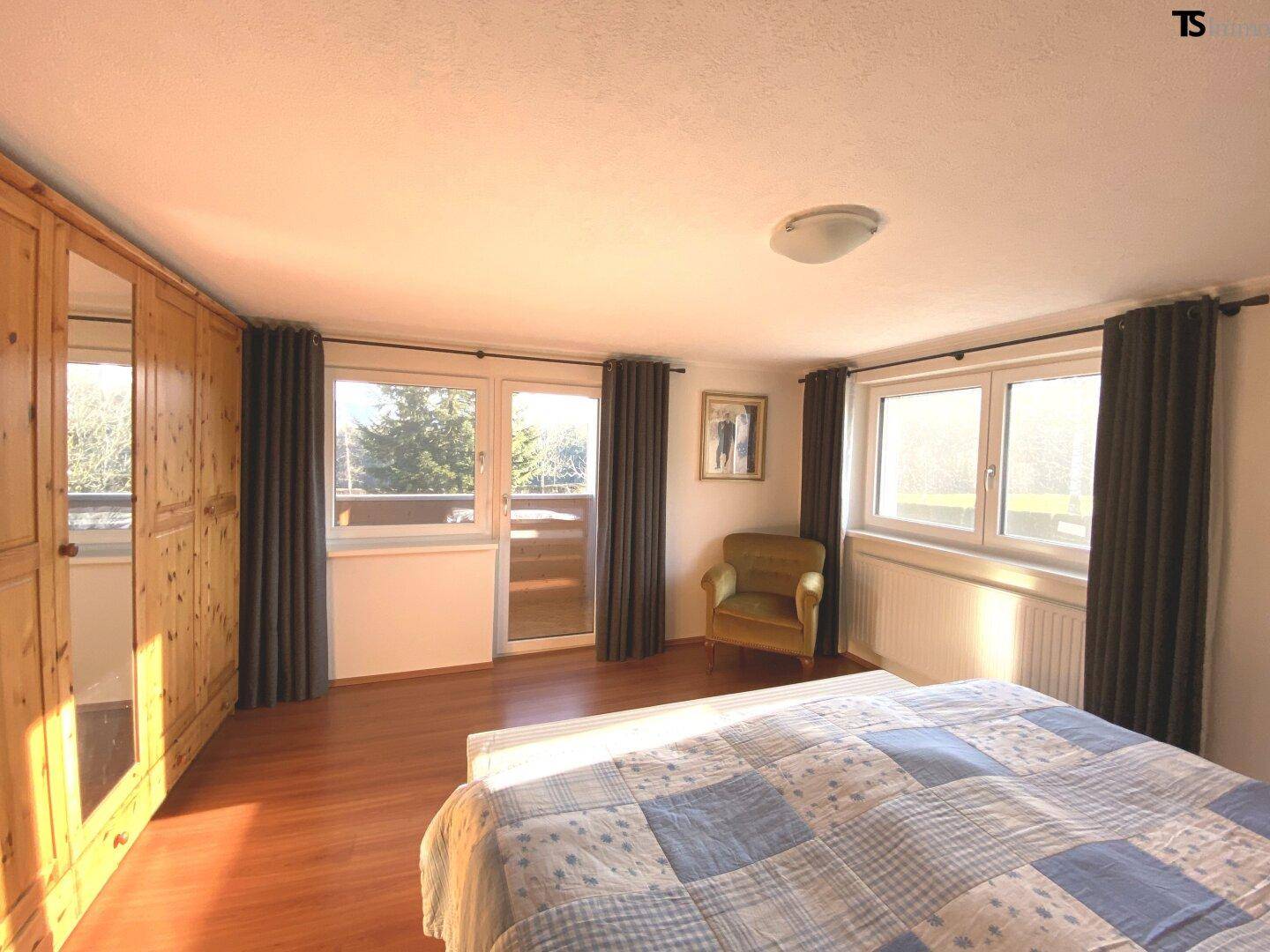 Helles Schlafzimmer mit Holzboden, großem Kleiderschrank und Balkonzugang.