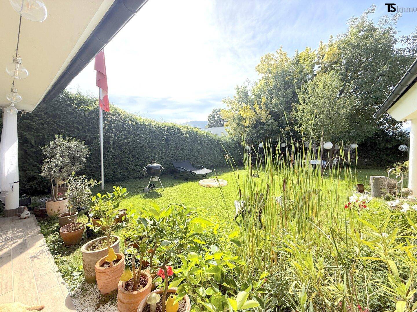 Gepflegter Gartenbereich mit hoher Hecke, Grillplatz und Liegemöglichkeit.