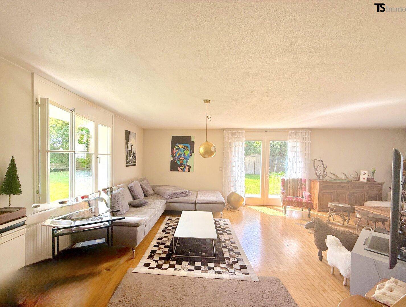 Geräumiges Wohnzimmer mit Parkettboden, großem Sofa und Zugang zum Garten.