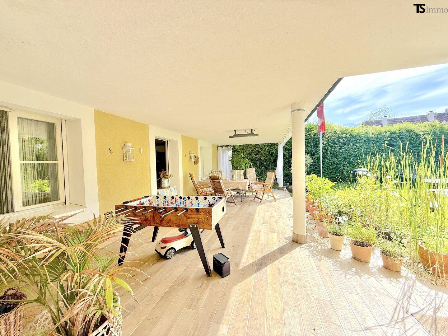 Geräumige, überdachte Terrasse mit Fliesenboden, Tischfußball und Essbereich.