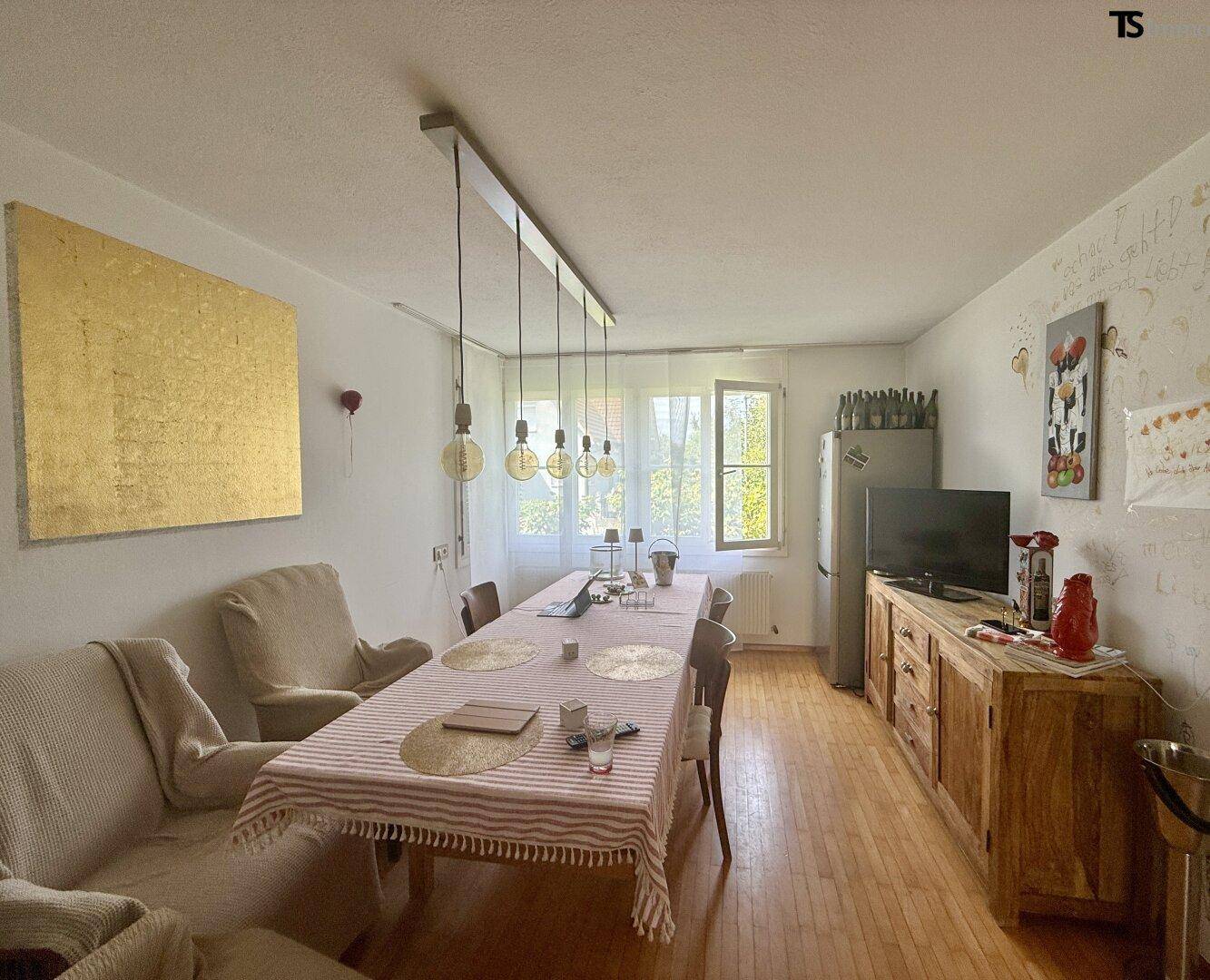Gemütlicher Essbereich mit Holzboden, großem Esstisch und Fenster.