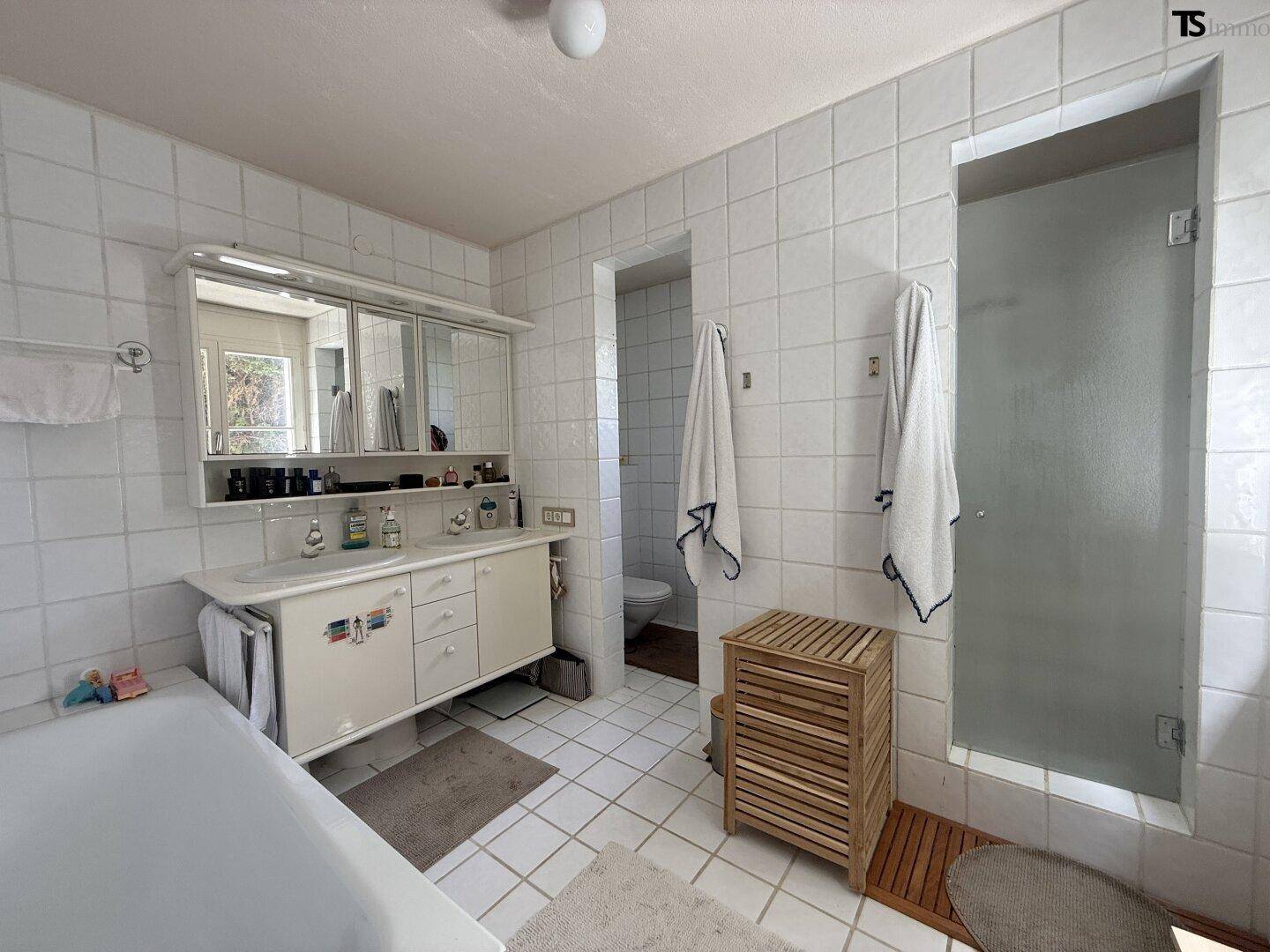 Gefliestes Badezimmer mit Badewanne, Dusche und Doppelwaschbecken.
