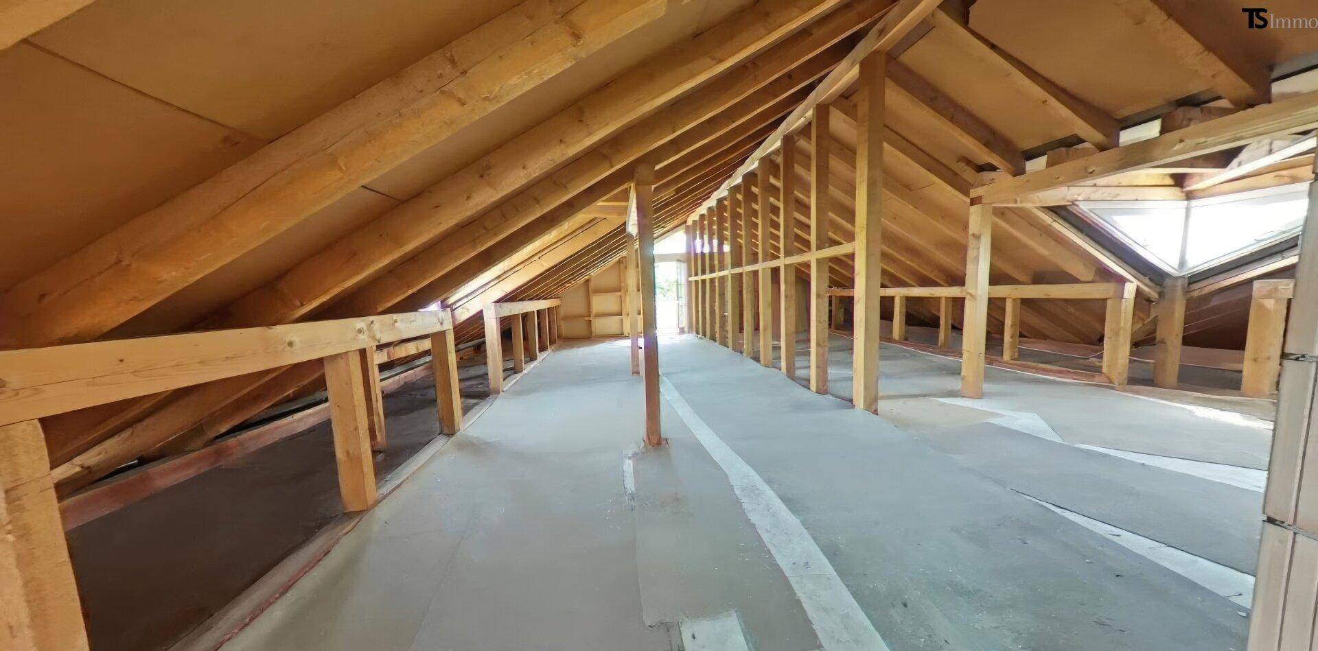 Unausgebauter Dachboden mit sichtbarer Holzkonstruktion und Dachfenster.