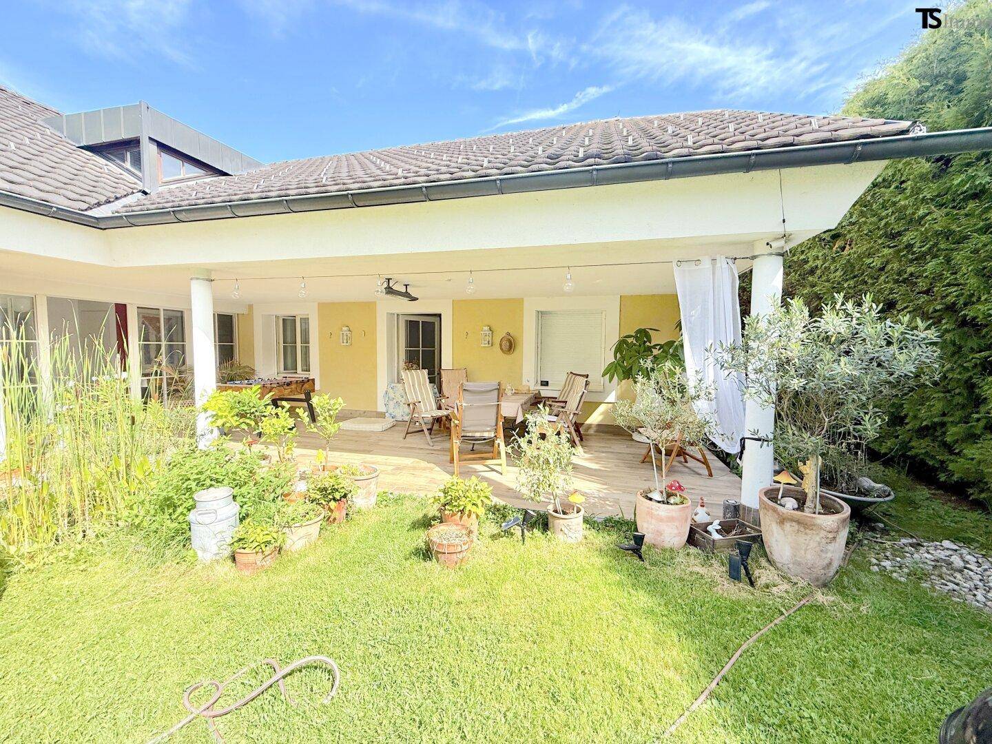 Überdachte Terrasse mit Gartenmöbeln und Blick auf den gepflegten Garten.