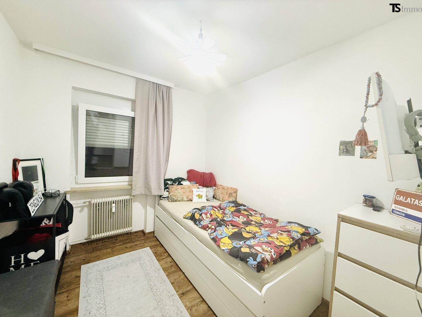 Helles Kinderzimmer mit Einzelbett, Stauraum und Fenster für natürliches Licht.