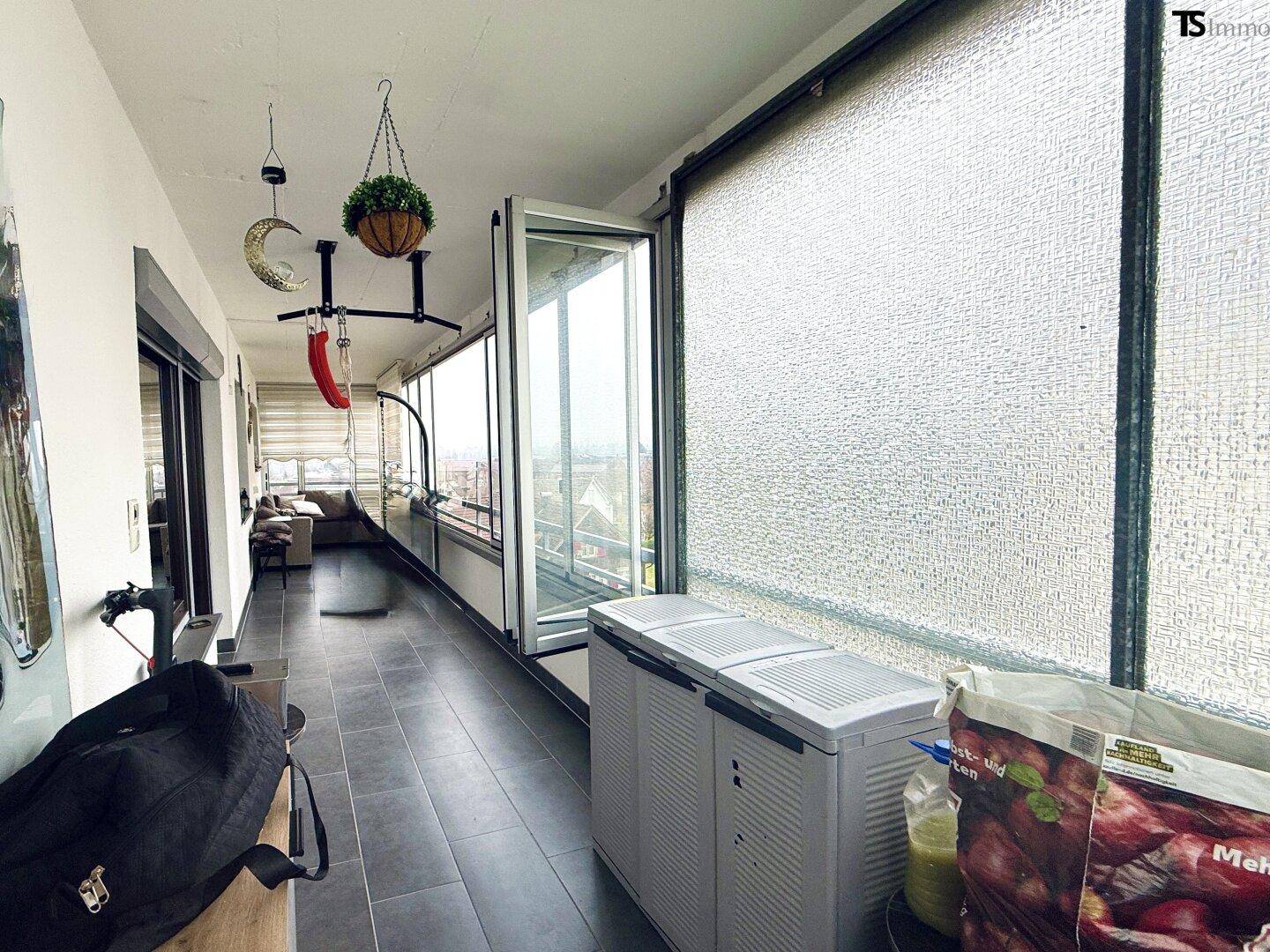 Verglaste Loggia mit Fliesenboden und weitem Blick, ideal für Entspannung.