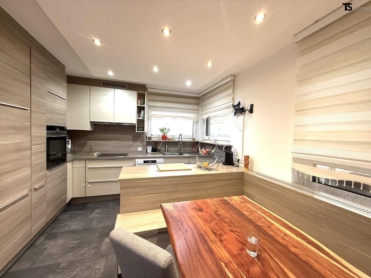 Funktionale Küche mit Essbereich an der Kücheninsel, Holzfronten und modernen Geräten.