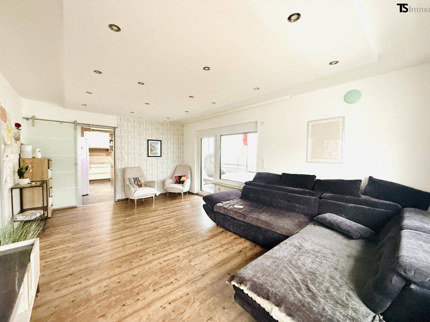 Gemütliches Wohnzimmer mit großem Ecksofa und warmem Holzfußboden, ideal zum Entspannen.