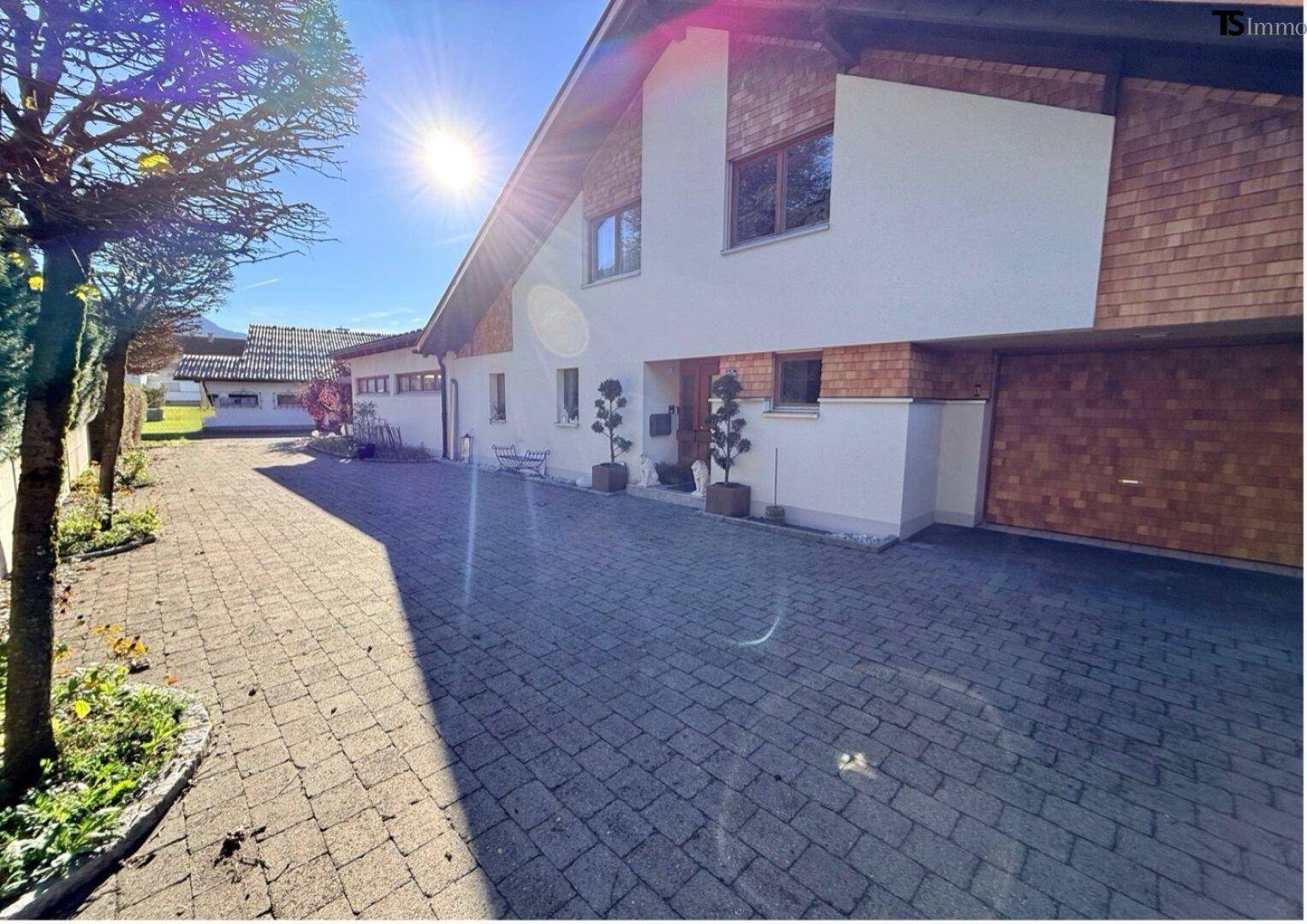 Vorderansicht des Hauses mit gepflasterter Auffahrt und Holzelementen an der Fassade.